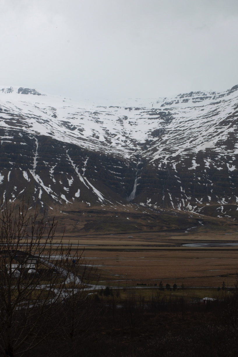 Chute d'eau dans la montagne enneigée face à Fjarðabyggð