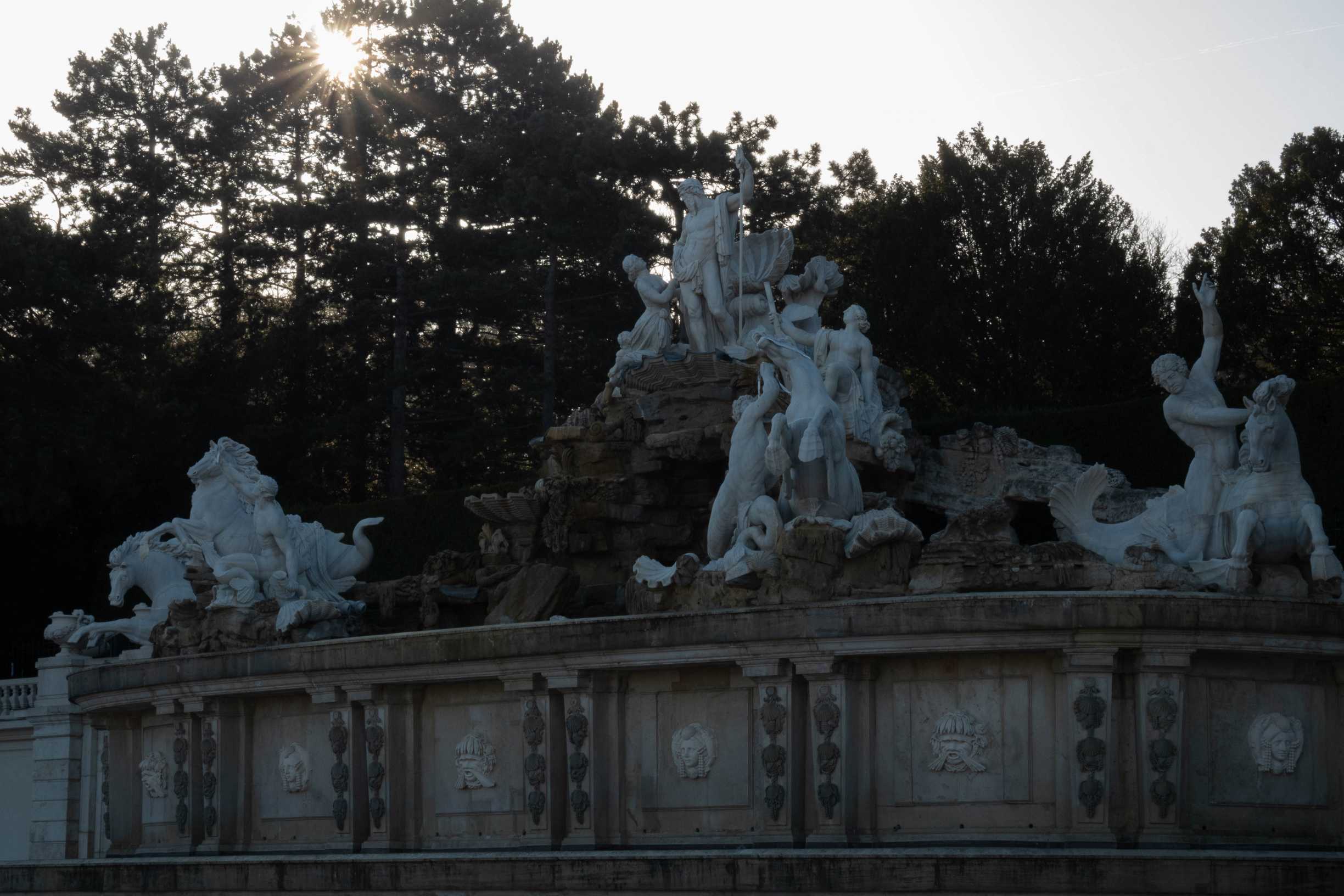La fontaine de Neptune et ses statues avec le soleil derrière